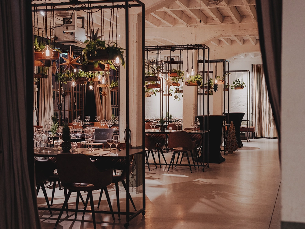 Ein stilvoll dekoriertes Restaurant, mit Pflanzen und warmem Licht, deckt Tische für ein Abendessen in einem eleganten, modernen Raum.