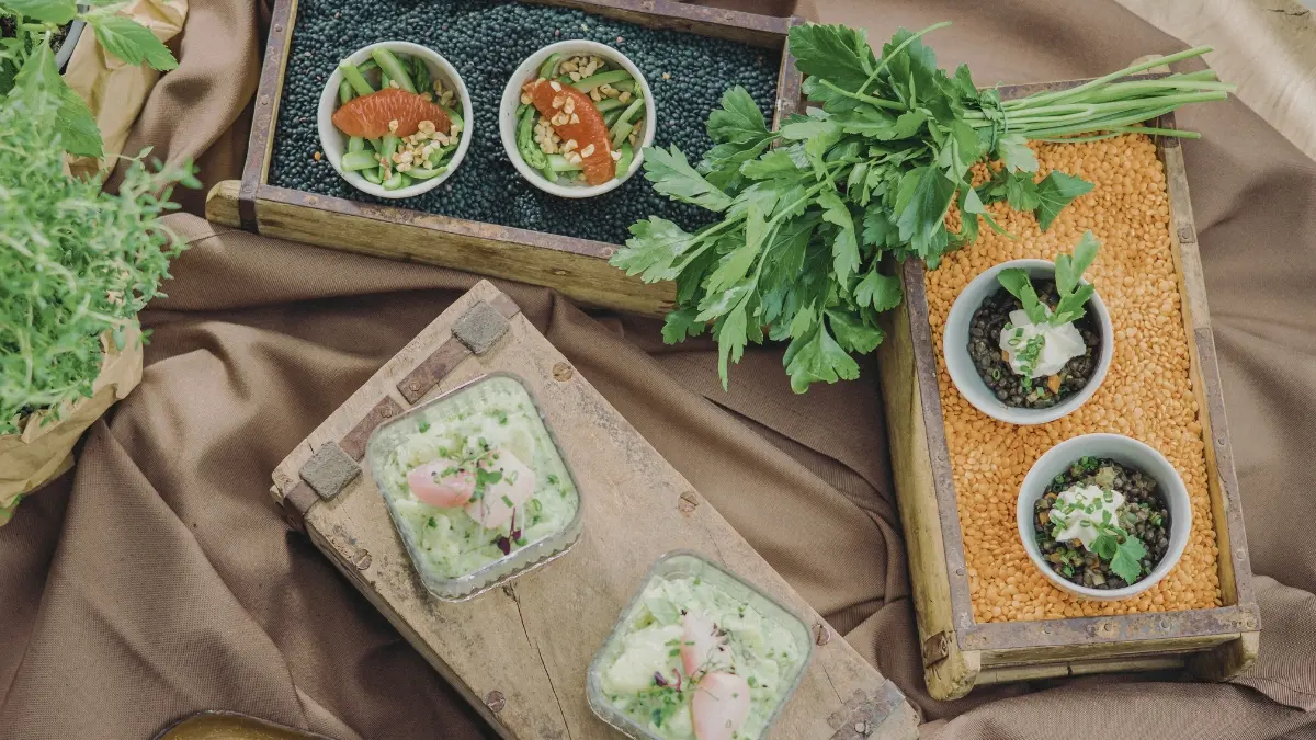 Verschiedene vegetarische Gerichte in Schalen auf Linsen und schwarzen Bohnen, mit Grünkohlblättern dekoriert.