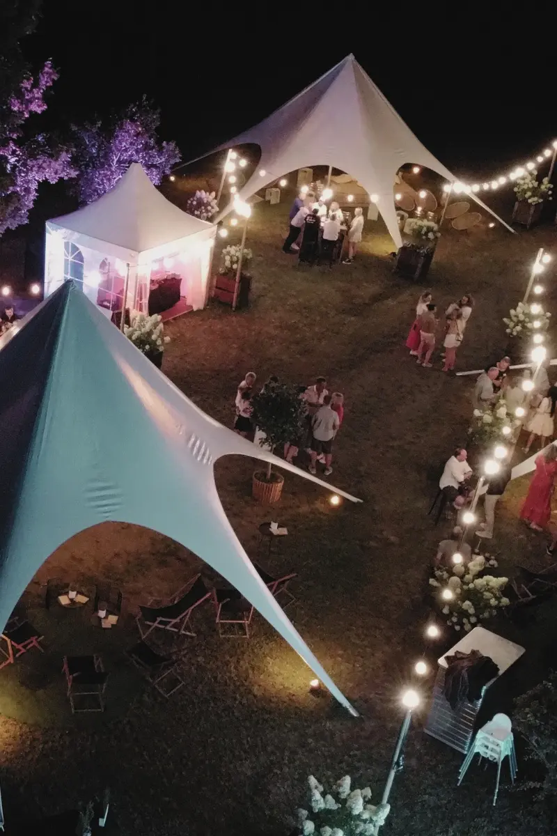 VC_Website_Location_Sommer-Location_Langenbrettach (1) Nachtszene eines Gartenfests mit beleuchteten Pavillons, Gästen in Feierlaune und dekorativen Lichterketten.